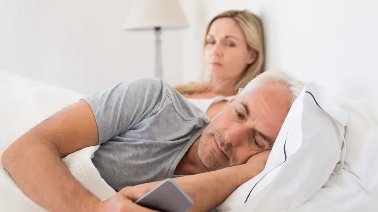 Un homme, absorbé par son téléphone, ignore sa femme. Les signes d'un homme amoureux de sa maîtresse sont subtils, mais son regard ailleurs en dit long.