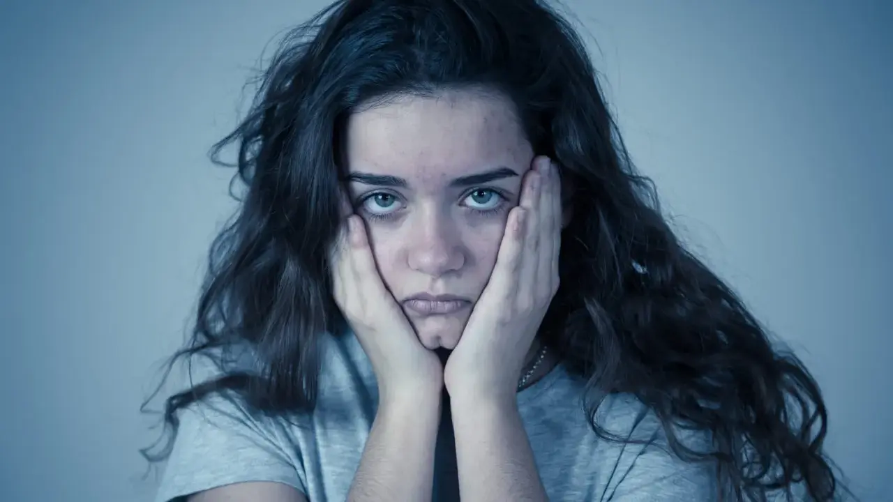 Jeune femme aux mains sur les joues, regard perdu. Elle semble passer un test de sociopathe, l'air accablé.