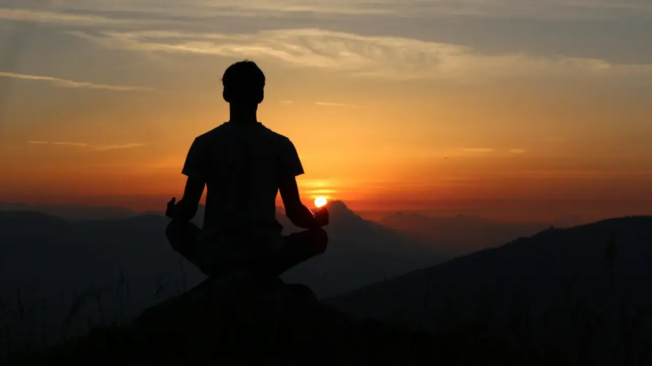 Silhouette d'une personne méditant au coucher du soleil. Une scène paisible pour travailler avec son ex, trouver la sérénité.