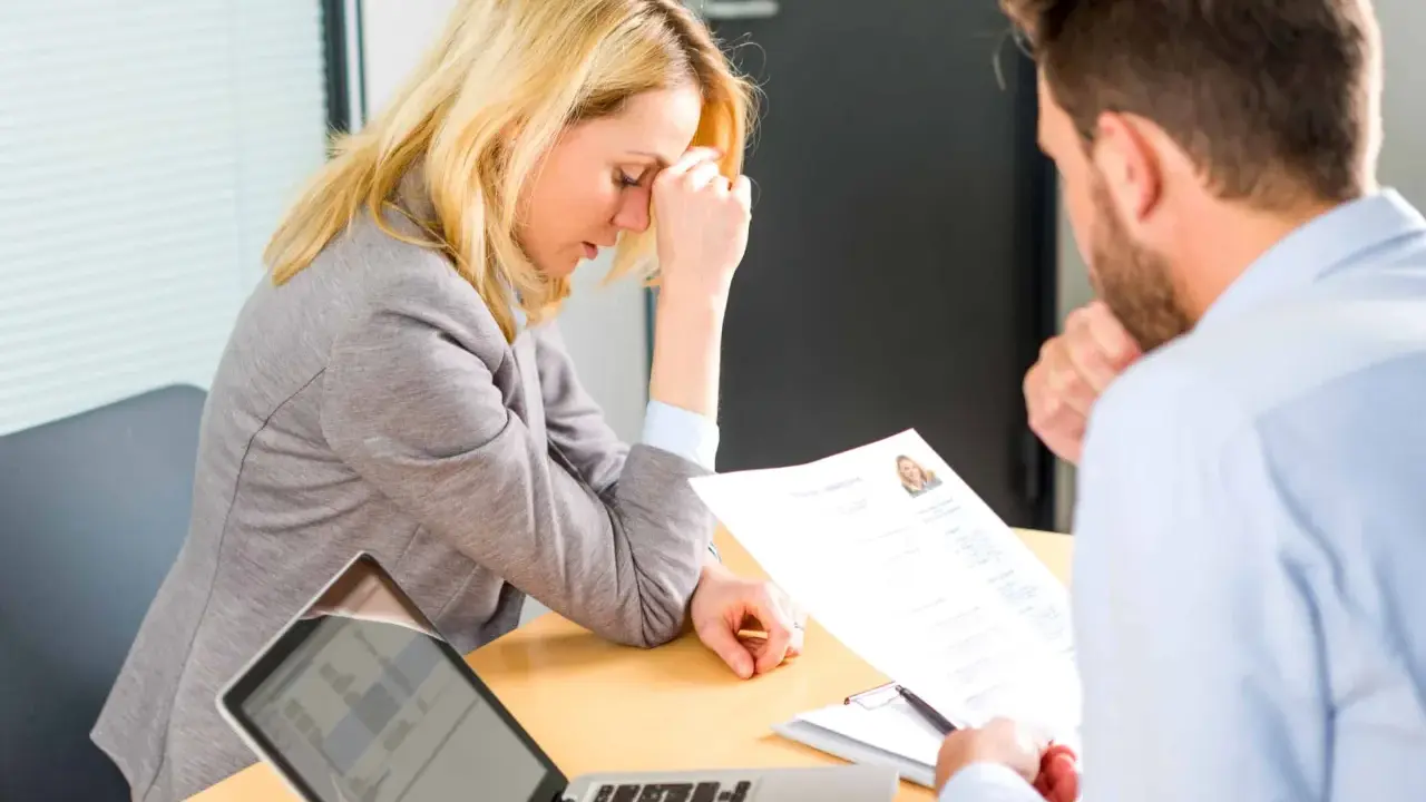 Une femme stressée lors d'un entretien d'embauche, face à un recruteur qui examine son CV. Un test pour déceler un pervers narcissique au travail.