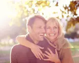 Un couple souriant, peut-être traversant une crise de la cinquantaine, mais l'infidélité semble loin. Lumière dorée d'automne.