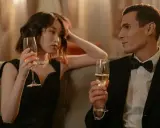 Un homme en smoking et une femme en robe noire sirotent du champagne, une scène qui pourrait inspirer sur comment séduire une fille.