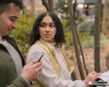 Un homme qui trompe et ment, regardant son téléphone, tandis qu'une femme se méfie, assise à côté de lui dans un parc.