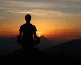 Silhouette d'une personne méditant au coucher du soleil. Une scène paisible pour travailler avec son ex, trouver la sérénité.