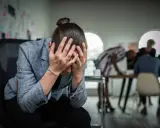 Personse tenant la tête entre les mains, visiblement stressée. Un test d'anxiété sociale pourrait révéler son état.