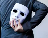 Une main cache un masque blanc derrière un costume. "Je suis narcissique, que faire ?" se demande la personne.