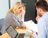 Une femme stressée lors d'un entretien d'embauche, face à un recruteur qui examine son CV. Un test pour déceler un pervers narcissique au travail.