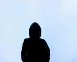Silhouette d'une personne sous une capuche, le regard perdu dans le brouillard. Une image qui évoque la solitude, le mystère, et peut-être la présence d'une manipulatrice narcissique cachée.