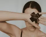 Femme cachant son visage avec sa main, ornée de deux croix noires.