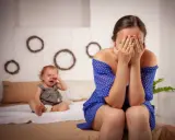 Une mère désespérée cache son visage, son bébé pleure. Je ne supporte plus ma vie de famille.