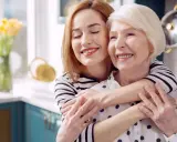 Une jeune femme enlace tendrement sa mère. Après une période difficile, peut-être une maman hospitalisée, elles partagent un moment de joie et de soulagement.