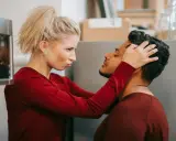Une femme possessive ajuste la tête de son partenaire, le regardant avec une expression intense.