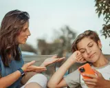 Une mère parle à son fils, qui semble désintéressé, son téléphone à la main. Un test schizoïde pourrait évaluer ce type de déconnexion.