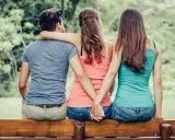 Trois personnes assises sur un banc, deux femmes se tenant la main dans le dos, un homme au milieu. Une scène qui interroge sur comment faire avouer à un homme qu'il vous trompe.