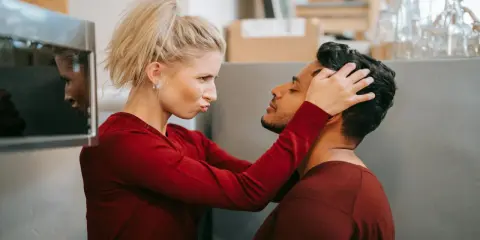 Une femme possessive ajuste la tête de son partenaire, le regardant avec une expression intense.