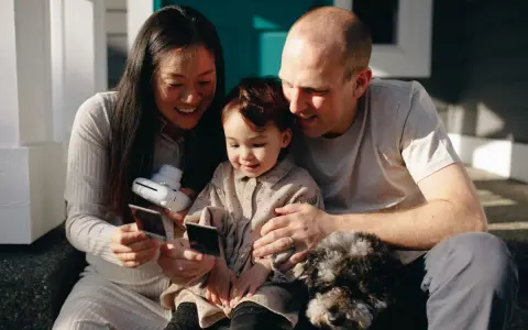 Famille heureuse regardant des photos instantanées, une annonce grossesse fratrie en préparation.