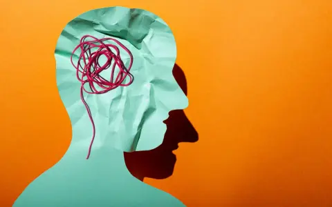 Silhouette d'une tête en papier froissé, avec un fil rouge emmêlé symbolisant la pensée complexe d'un esprit hpi neuroatypique.