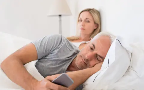 Un homme, absorbé par son téléphone, ignore sa femme. Les signes d'un homme amoureux de sa maîtresse sont subtils, mais son regard ailleurs en dit long.