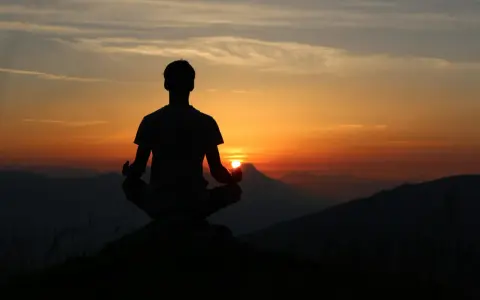Silhouette d'une personne méditant au coucher du soleil. Une scène paisible pour travailler avec son ex, trouver la sérénité.