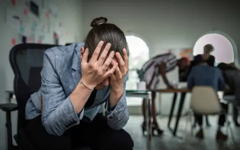 Personse tenant la tête entre les mains, visiblement stressée. Un test d'anxiété sociale pourrait révéler son état.