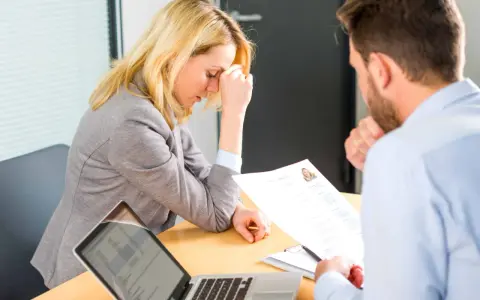 Une femme stressée lors d'un entretien d'embauche, face à un recruteur qui examine son CV. Un test pour déceler un pervers narcissique au travail.