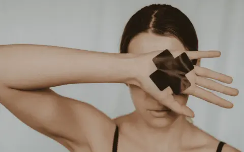 Femme cachant son visage avec sa main, ornée de deux croix noires.