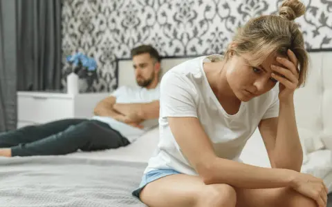 Une femme trompe son mari. Elle est assise sur le lit, la tête dans les mains, le regard perdu. Son mari, dos à elle, semble en colère.