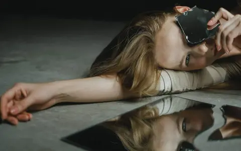 Une femme regarde des éclats de miroir, se demandant : "Suis-je narcissique ?" Son reflet brisé pose la question.