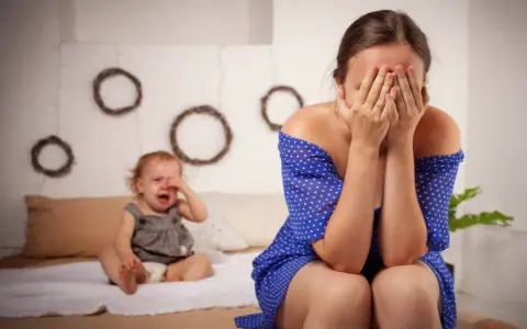 Une mère désespérée cache son visage, son bébé pleure. Je ne supporte plus ma vie de famille.