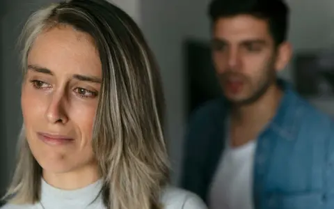 Une femme au regard triste, un homme flou en arrière-plan. Pourquoi un homme cache qu'il a une copine ? Une situation compliquée.