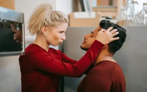 Une femme possessive ajuste la tête de son partenaire, le regardant avec une expression intense.