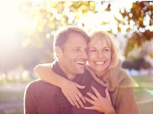 Un couple souriant, peut-être traversant une crise de la cinquantaine, mais l'infidélité semble loin. Lumière dorée d'automne.