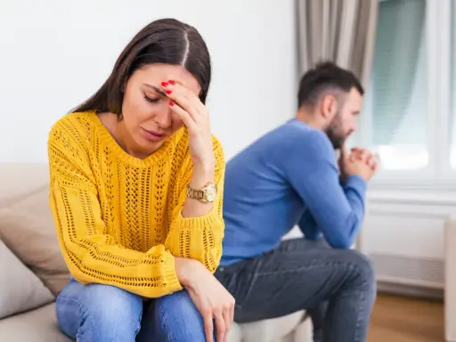 Une femme désemparée se tient la tête, son mari pensif est assis dos à elle. Elle se demande comment savoir si mon mari me trompe.