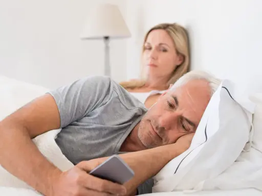 Un homme, absorbé par son téléphone, ignore sa femme. Les signes d'un homme amoureux de sa maîtresse sont subtils, mais son regard ailleurs en dit long.