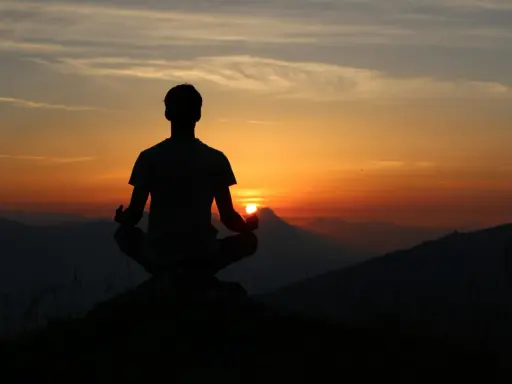 Silhouette d'une personne méditant au coucher du soleil. Une scène paisible pour travailler avec son ex, trouver la sérénité.
