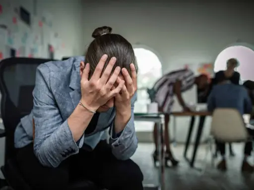 Personse tenant la tête entre les mains, visiblement stressée. Un test d'anxiété sociale pourrait révéler son état.