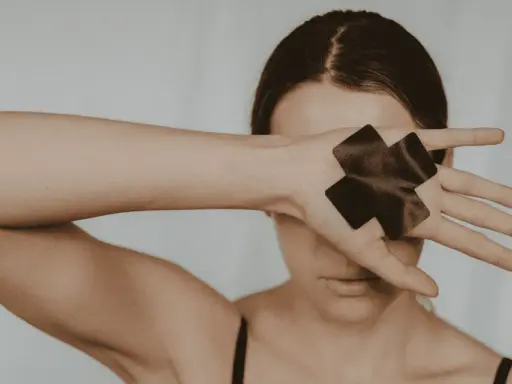 Femme cachant son visage avec sa main, ornée de deux croix noires.
