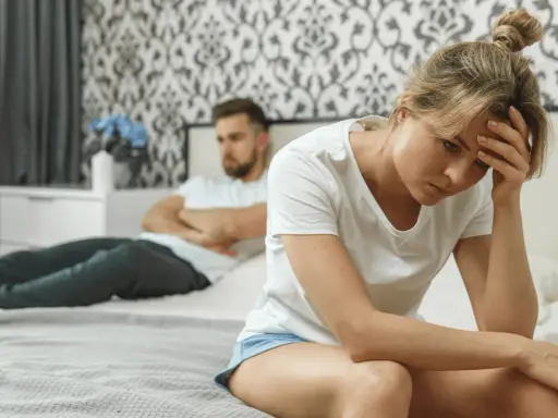 Une femme trompe son mari. Elle est assise sur le lit, la tête dans les mains, le regard perdu. Son mari, dos à elle, semble en colère.