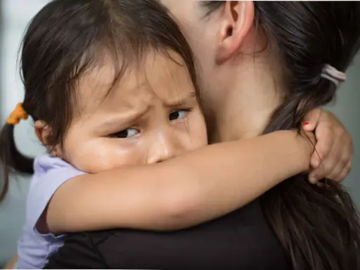 Un enfant serre sa mère, le regard plein d'angoisse de séparation.