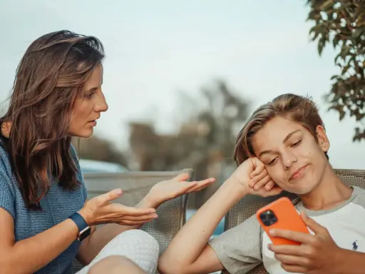 Une mère parle à son fils, qui semble désintéressé, son téléphone à la main. Un test schizoïde pourrait évaluer ce type de déconnexion.