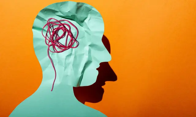 Silhouette d'une tête en papier froissé, avec un fil rouge emmêlé symbolisant la pensée complexe d'un esprit hpi neuroatypique.