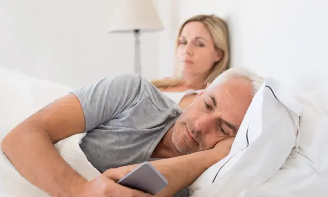 Un homme, absorbé par son téléphone, ignore sa femme. Les signes d'un homme amoureux de sa maîtresse sont subtils, mais son regard ailleurs en dit long.