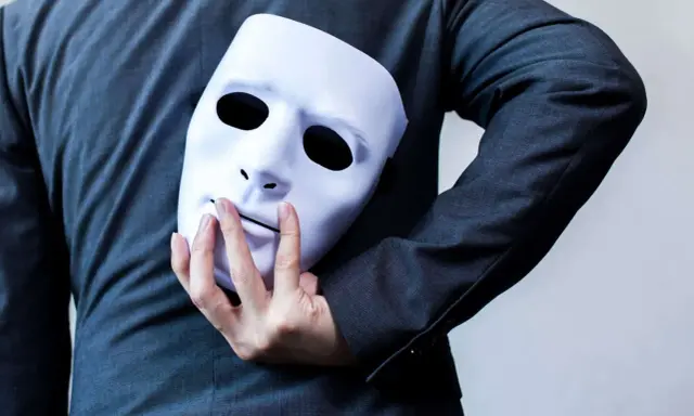 Une main cache un masque blanc derrière un costume. "Je suis narcissique, que faire ?" se demande la personne.