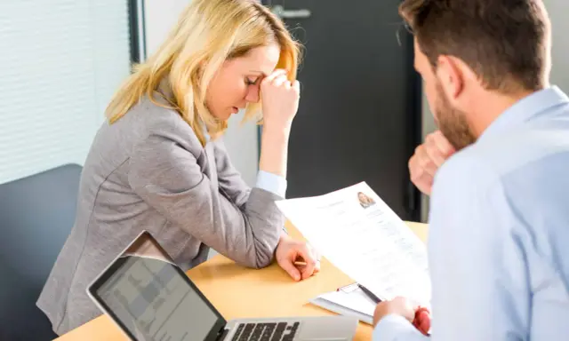 Une femme stressée lors d'un entretien d'embauche, face à un recruteur qui examine son CV. Un test pour déceler un pervers narcissique au travail.