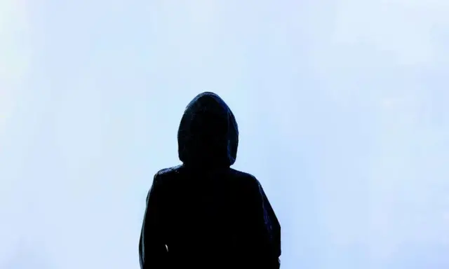 Silhouette d'une personne sous une capuche, le regard perdu dans le brouillard. Une image qui évoque la solitude, le mystère, et peut-être la présence d'une manipulatrice narcissique cachée.