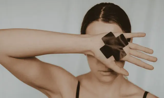 Femme cachant son visage avec sa main, ornée de deux croix noires.