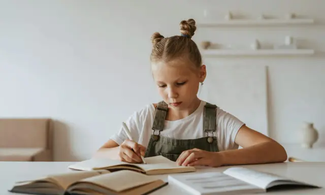 Jeune fille concentrée sur son cahier, peut-être en pleine préparation d'un test HPI WISC.