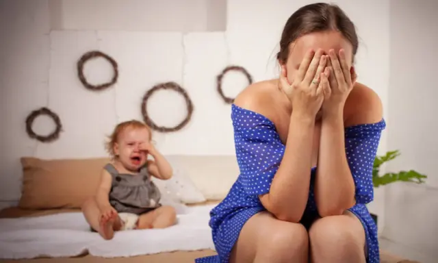 Une mère désespérée cache son visage, son bébé pleure. Je ne supporte plus ma vie de famille.
