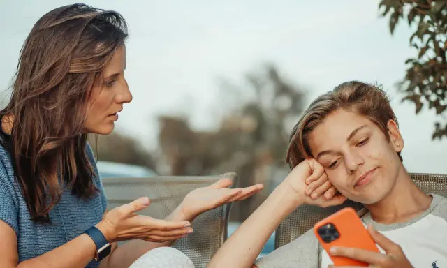 Une mère parle à son fils, qui semble désintéressé, son téléphone à la main. Un test schizoïde pourrait évaluer ce type de déconnexion.