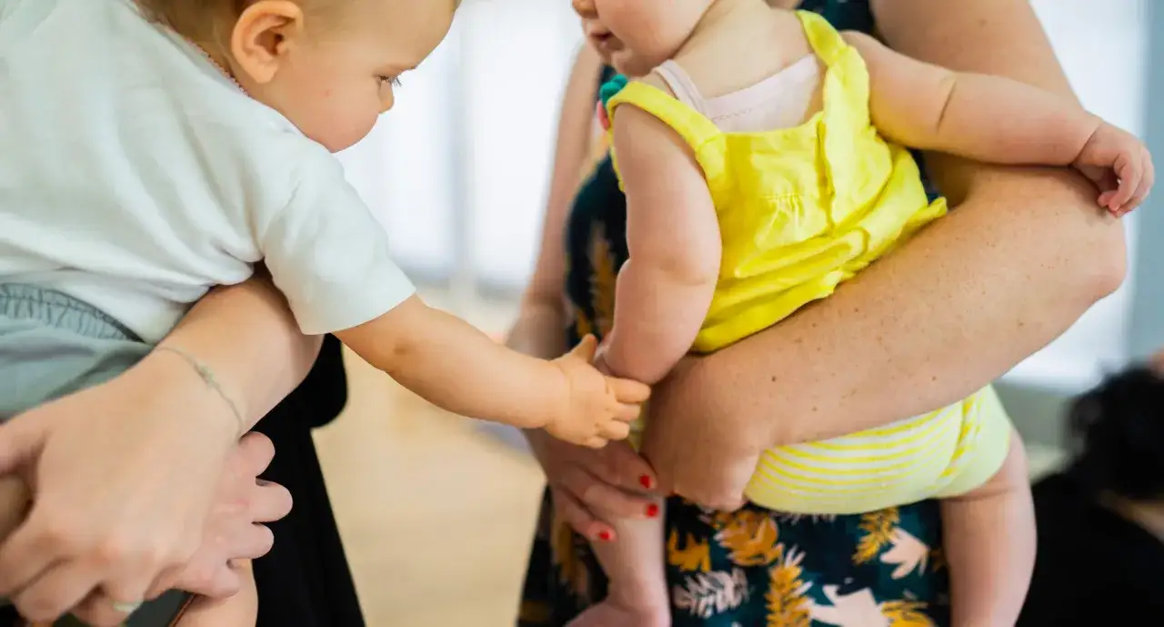 Deux b&eacute;b&eacute;s se tiennent la main, l'un en blanc, l'autre en jaune. L'un semble vouloir s'accrocher, signe d'angoisse de s&eacute;paration.